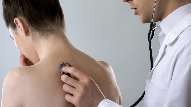 Médico ausculta o pulmão de uma paciente