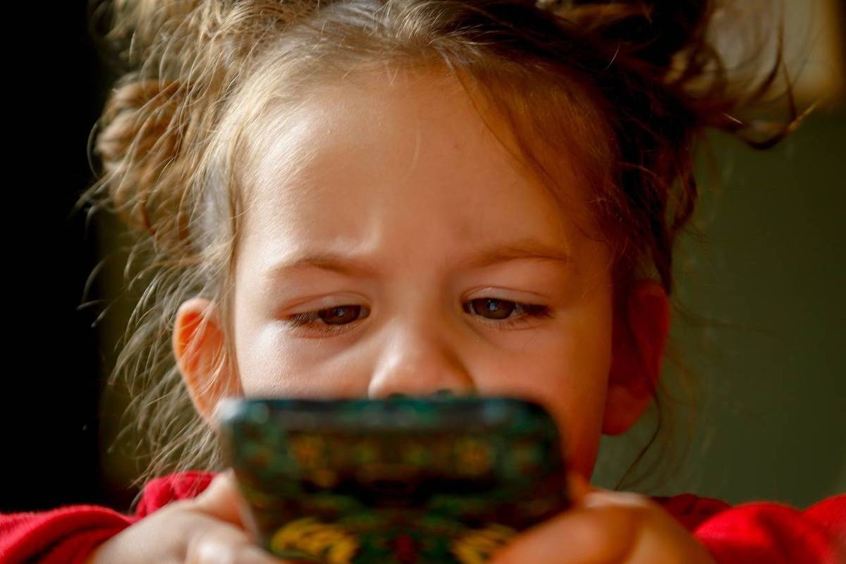 Menina olha fixamente para tela de celular