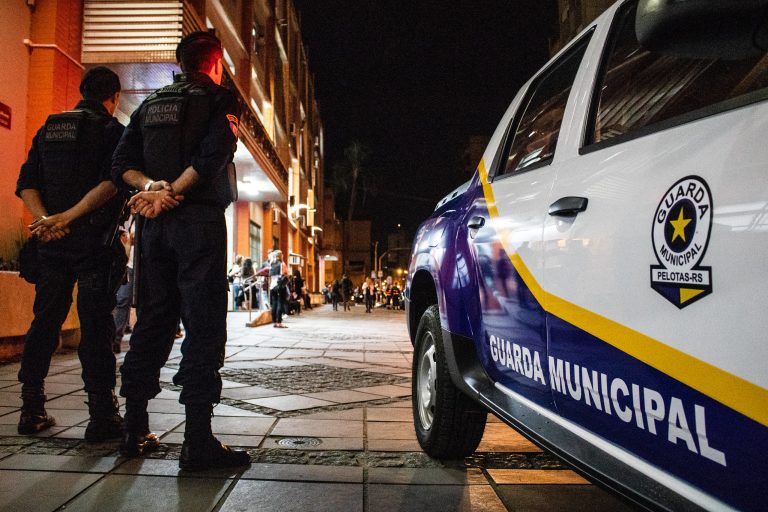 Guardas municipais ao lado de viatura na rua