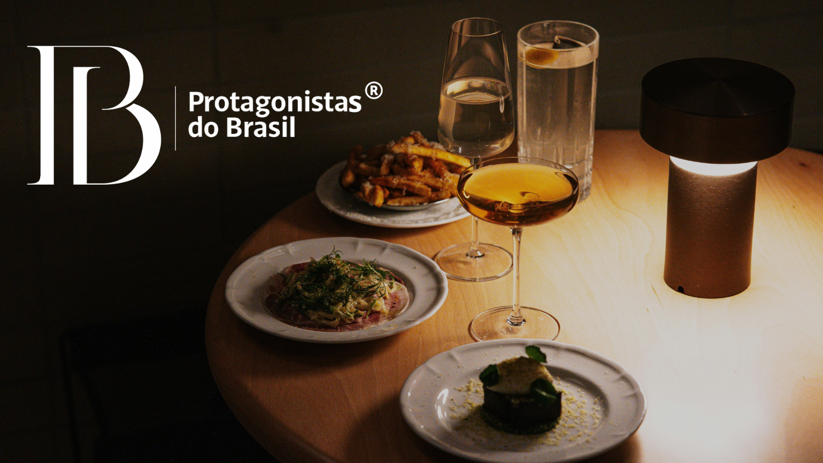 Mesa posta com pratos gourmet e drinks em ambiente intimista representando o jantar exclusivo do evento Protagonistas do Brasil.