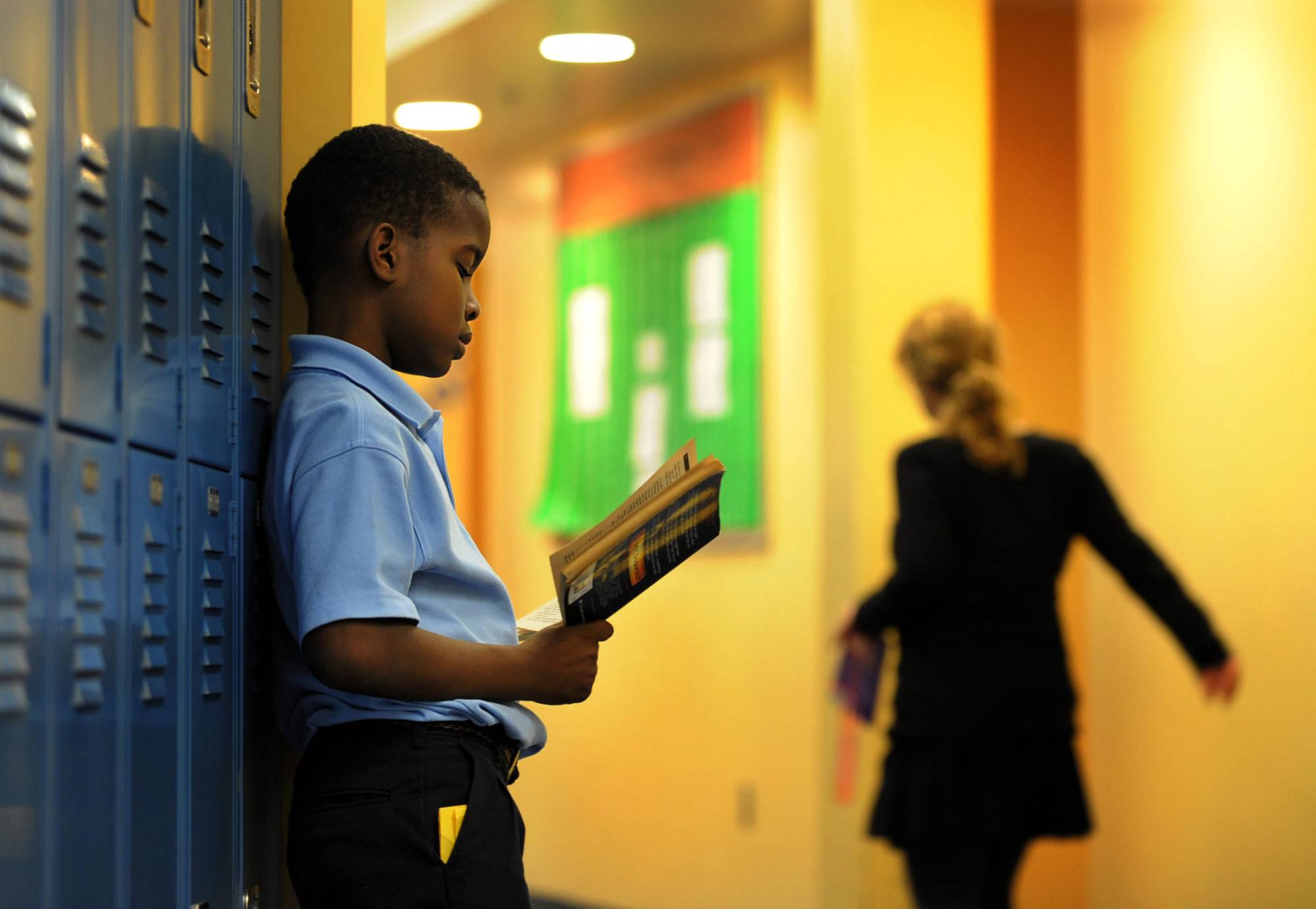 Boy reads a book in a school hallway