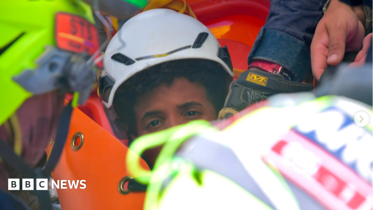 the picture shows half of the boys face - the rest is obscured by rescue workers. He