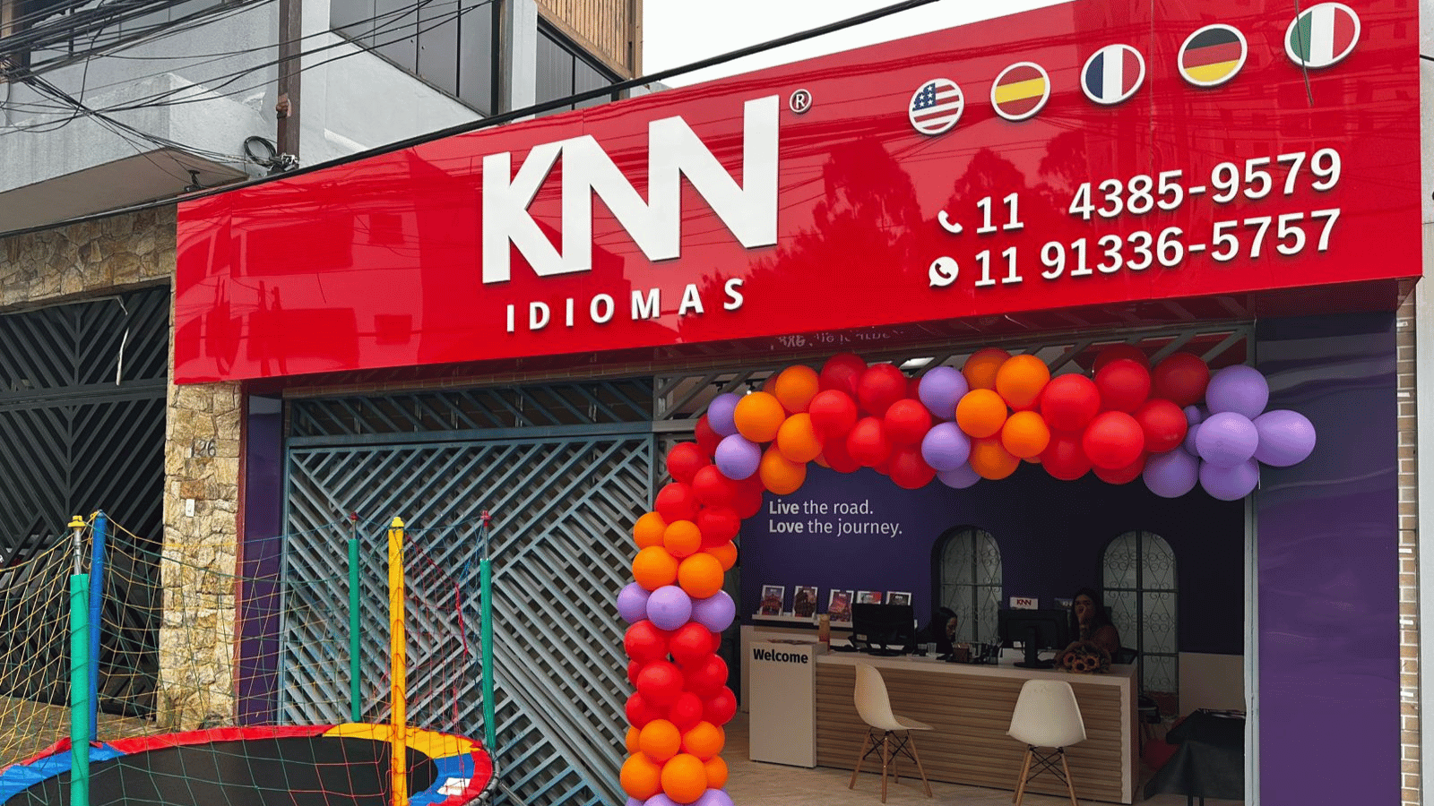 Fachada da KNN Idiomas em Taboão da Serra, São Paulo, com identidade visual da escola e entrada decorada com balões coloridos.